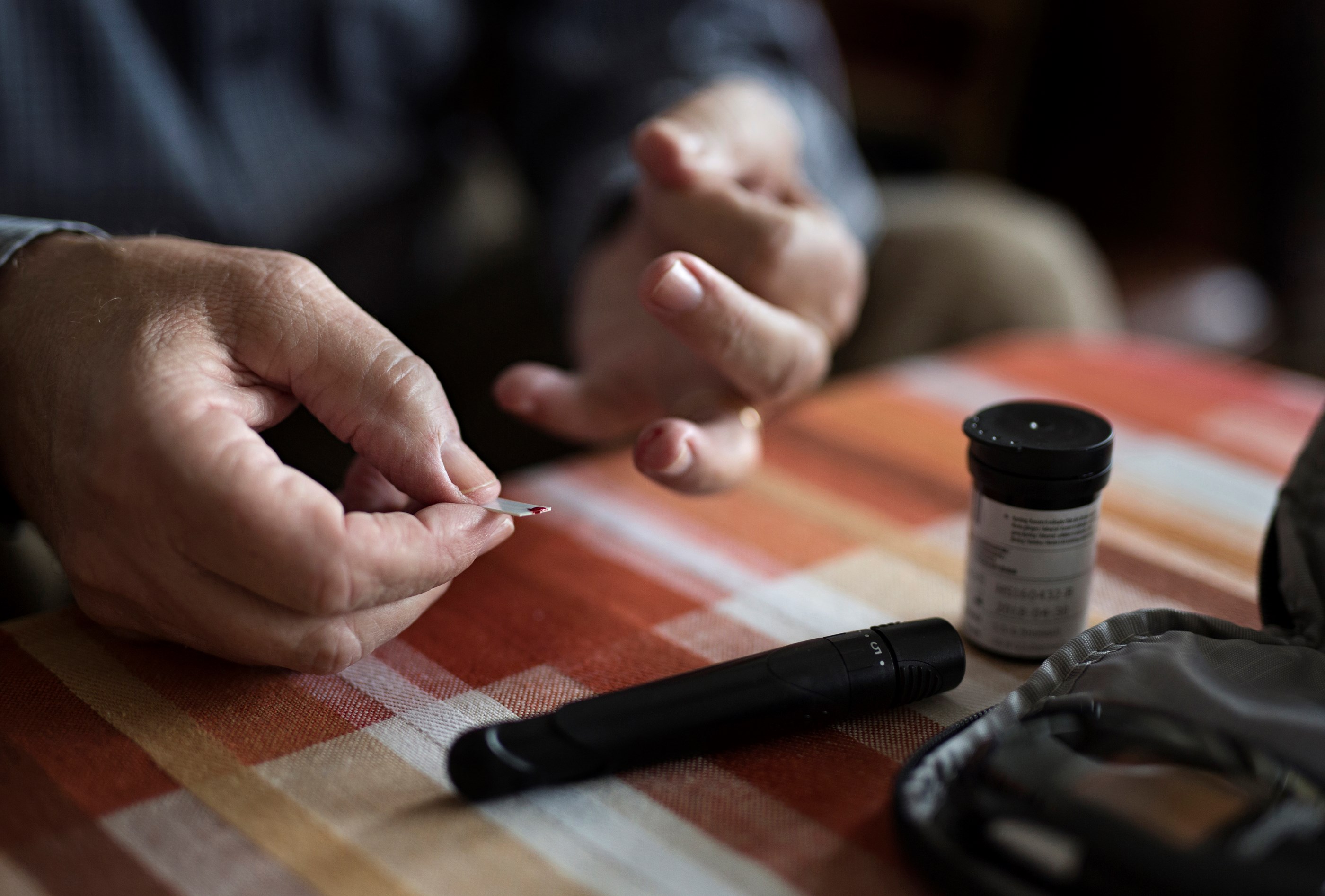 Billede af en fingerprikker og teststrimmel med bloddråbe