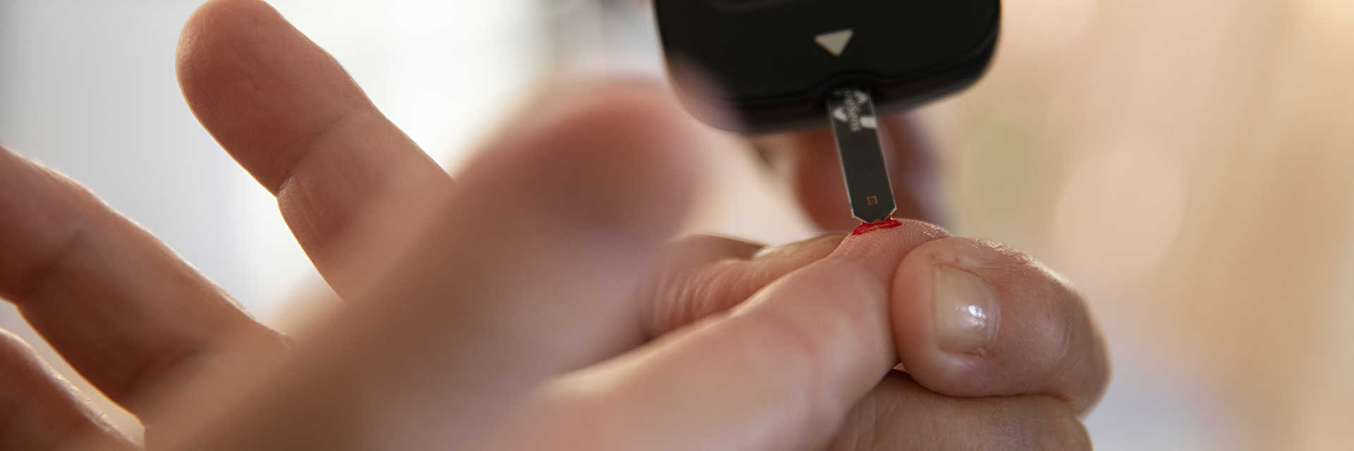 Billede af bloddråbe på finger og blodsukkermåling.